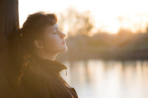 A woman meditates outside and enjoys her holistic addiction treatment