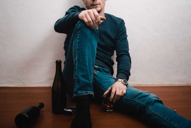 man sitting on floor struggling with alcohol and depression