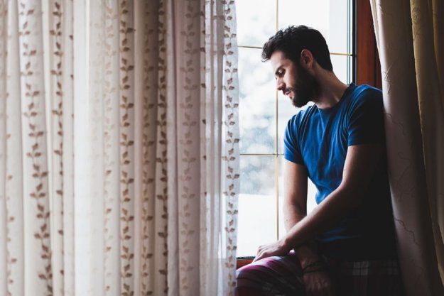 man looking out window in need of a North Carolina mental health treatment center